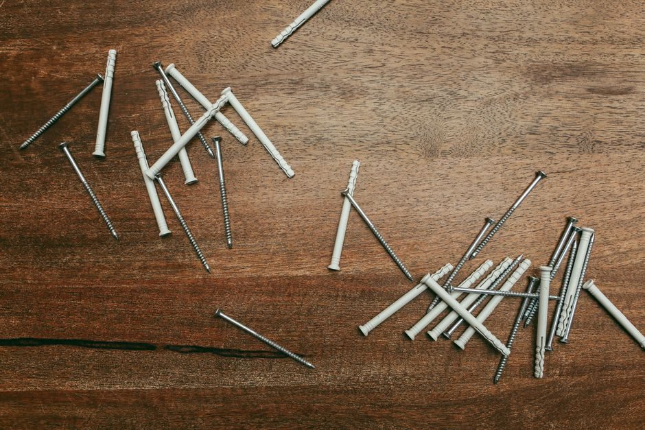 Close-up of nylon anchors and screws scattered on a wooden surface, perfect for DIY projects.