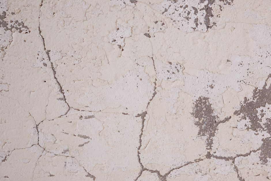High-resolution image of a cracked plaster wall texture with rough surface details, ideal for backgrounds and design.